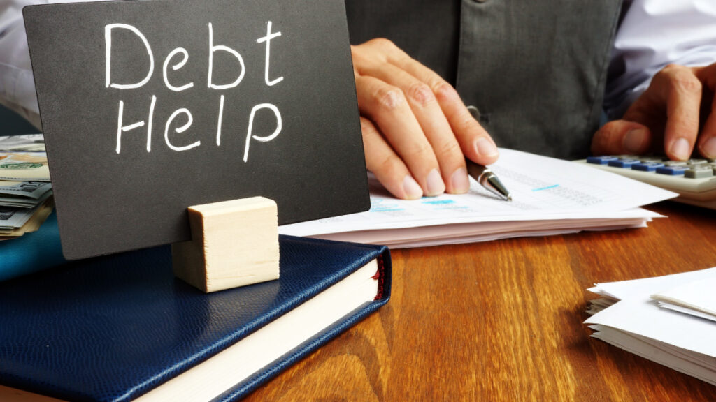 image of someone writing down information next to a sign that reads debt help