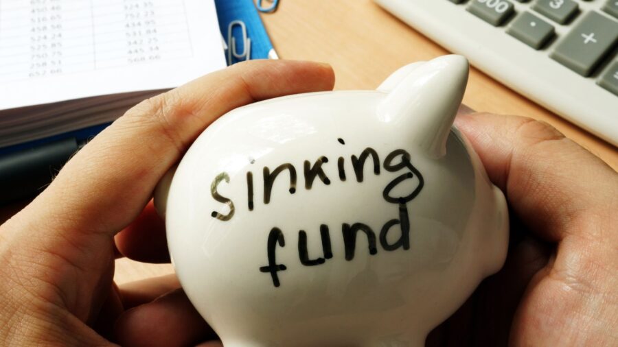 image of hands holding a piggy bank that reads 'sinking fund'