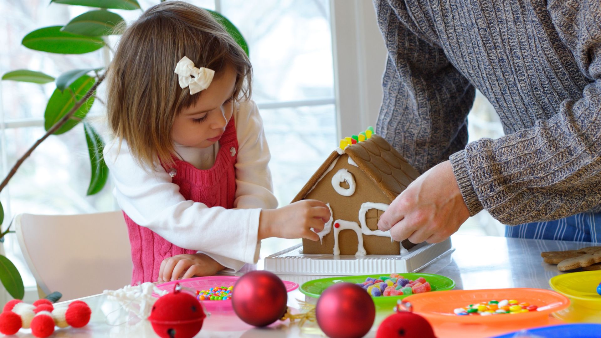 little girl decorating a gingerbread house